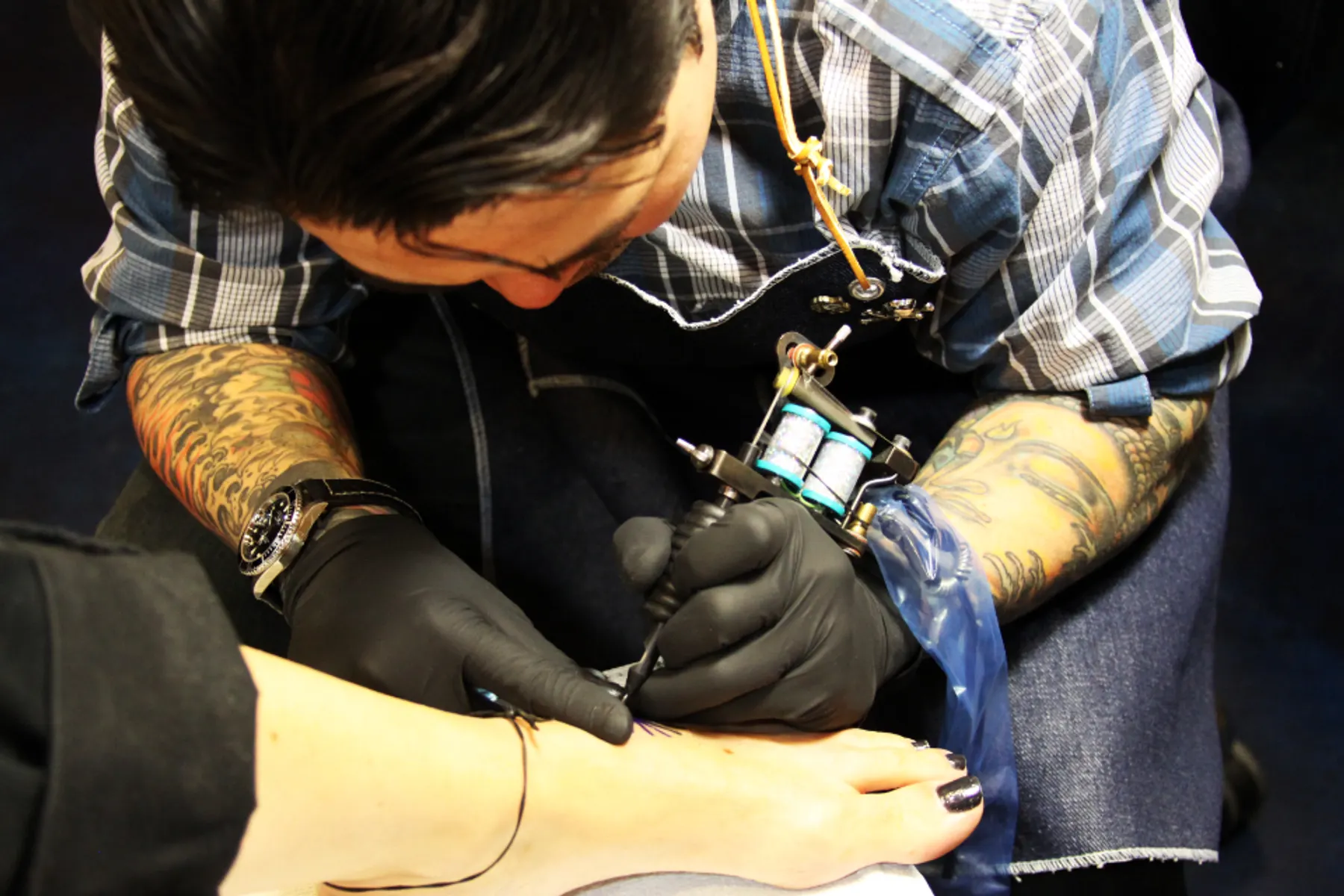 Tatuator przy pracy nad tatuażem na ramieniu